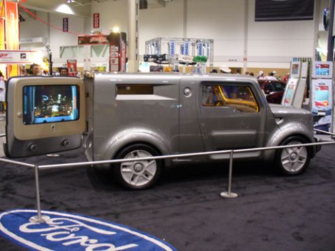 1995 Ford Taurus - A unique concept van is displayed with its rear door open, revealing an integrated screen showing a city view.