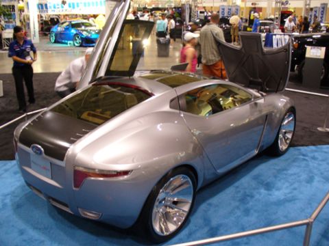 1995 Ford Taurus - Silver concept car with gullwing doors open at an auto show.