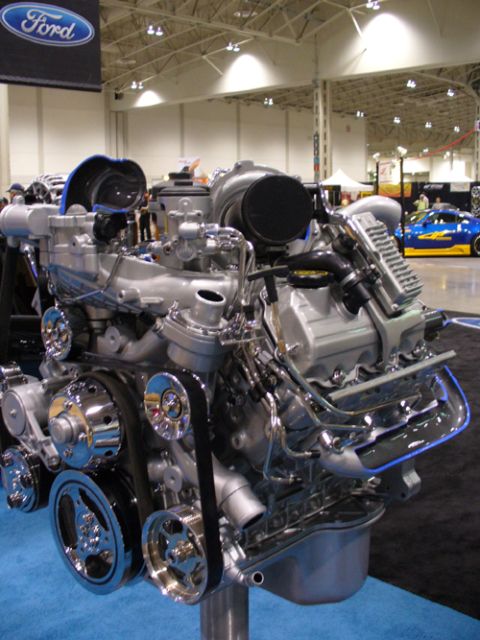 1995 Ford Taurus - A detailed view of a Ford V8 engine is presented, with a blue car visible in the background at an auto show.