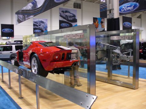 1995 Ford Taurus - A red Ford GT is displayed with its rear end visible, alongside a disassembled chassis.