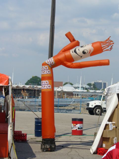 1995 Ford Taurus - An inflatable dancer advertises pizza with a cheerful face, standing near a construction area and a parked truck.