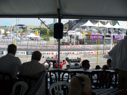 1995 Ford Taurus - Spectators watch a race from a covered area, with banners and tents visible in the background.