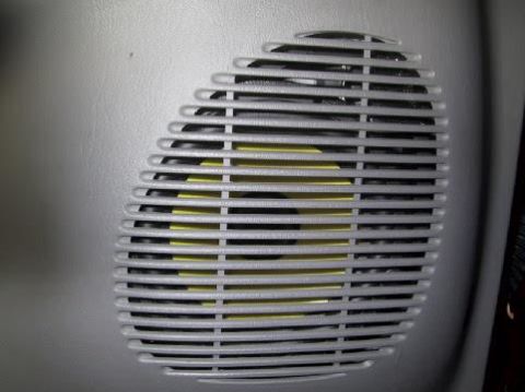 2001 Ford Excursion - A close-up of a vehicle's interior speaker grille shows the yellow speaker cone through its horizontal slats.