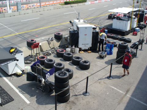 1995 Ford Taurus - A race track pit area is set up with numerous tires and support equipment, with a person walking through the scene.