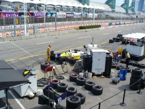 1995 Ford Taurus - A race car is being serviced on the pit lane with spare tires and equipment nearby.