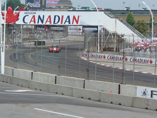 Red and white race car on a track, with Molson Canadian signage overhead