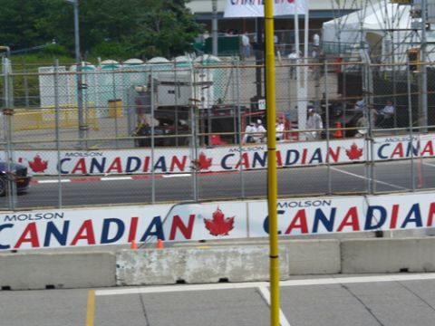 1995 Ford Taurus - A dark coupe is seen on a race track, with prominent Molson Canadian advertising banners in the background.