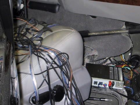 SUV interior with wiring bundles over gray seat and black electronic module on floor