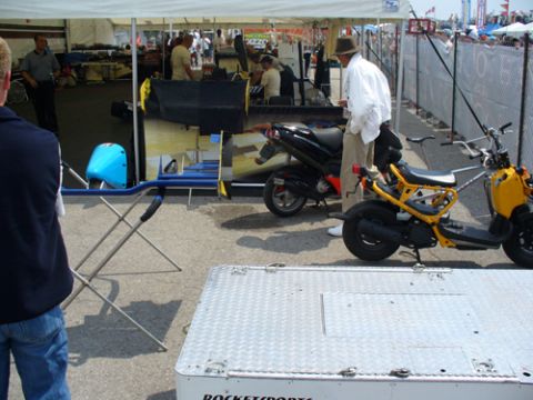 1995 Ford Taurus - Two scooters are parked outdoors under a tent, with people and various equipment visible in the background.