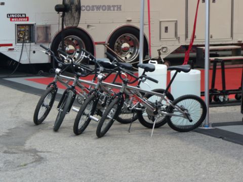 1995 Ford Taurus - Four bicycles are parked in front of a trailer that displays 'LINCOLN WELDERS' and 'COSOWORTH' branding.