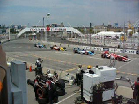 1995 Ford Taurus - Race cars compete on a track, with pit crews and Canadian banners visible in the background.