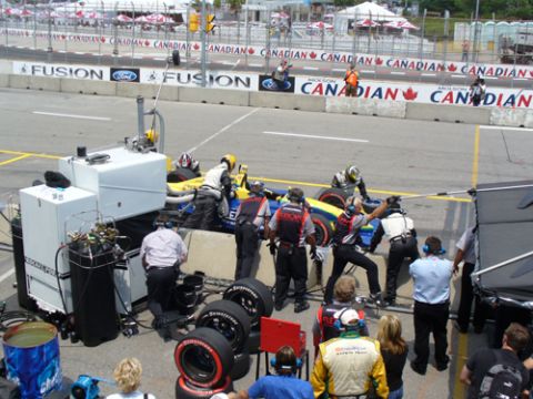 1995 Ford Taurus - A race car undergoes a pit stop with crew members working quickly to service it on the track.