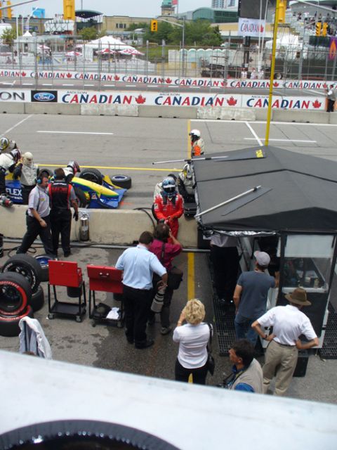 1995 Ford Taurus - A race car pit stop scene with crew members, media, and a driver preparing for action.