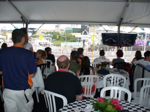 1995 Ford Taurus - People watch a race from a tented area with checkered tablecloths and screens displaying the event.