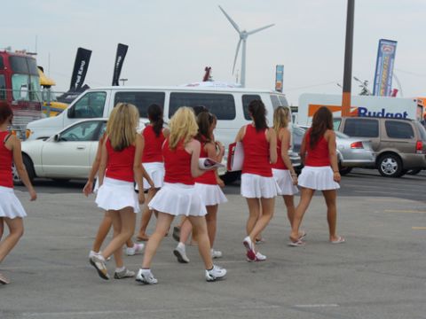 1995 Ford Taurus - Several women in matching outfits walk across a paved area with vehicles and a wind turbine in the background.