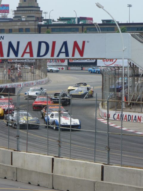 1995 Ford Taurus - Multiple race cars compete on a track under a large "CANADIAN" banner.
