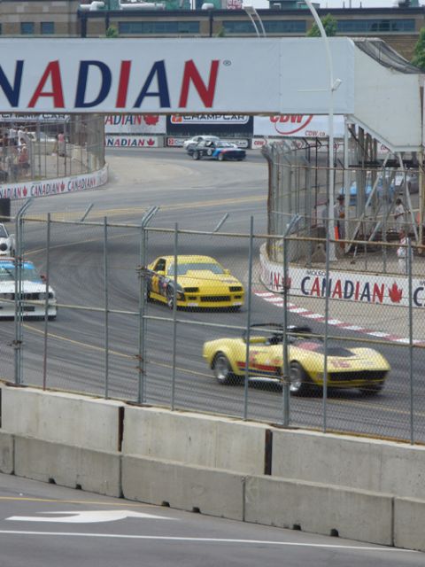 1995 Ford Taurus - Multiple race cars compete on a track under a large "CANADIAN" banner.