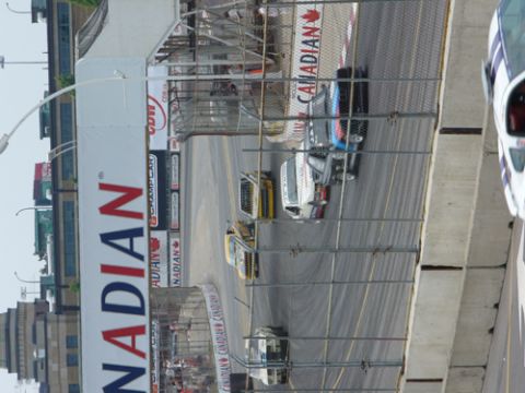 1995 Ford Taurus - Multiple race cars compete on a track with large Canadian branding visible on a banner.