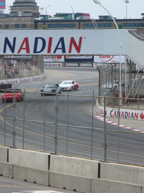1995 Ford Taurus - Multiple race cars compete on a track, with a large banner overhead reading "NADIAN".