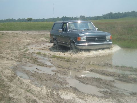 1988 Ford Bronco - This SUV navigates a muddy track, its body style indicating a 1987 model year.