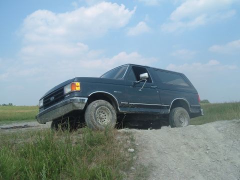 1988 Ford Bronco - Ford Bronco navigating rough terrain under a cloudy sky.