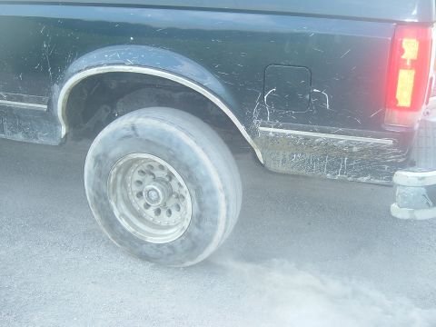 1988 Ford Bronco - Rear wheel of a 1988 Ford Bronco spinning on a dusty surface.