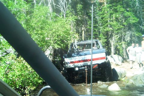 1966 Jeep CJ5 - This off-road vehicle, painted with an American flag motif, is shown navigating a rocky stream bed.