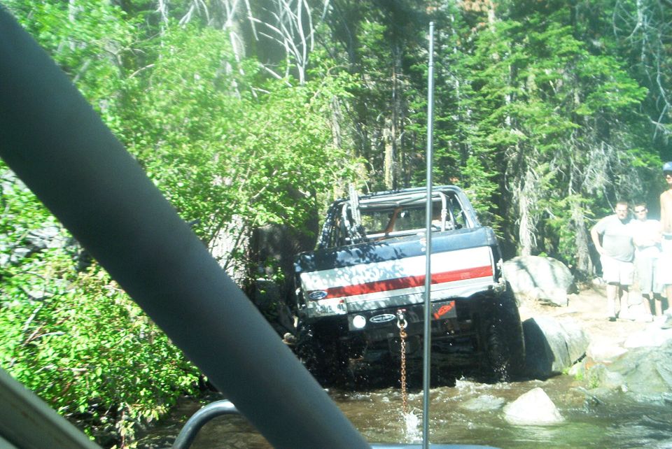 Off-road vehicle with American flag paint scheme navigating water and rocks