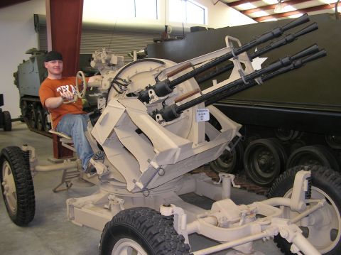 1966 Jeep CJ5 - A person sits in the operator's seat of a military anti-aircraft gun mount, with another vehicle in the background.