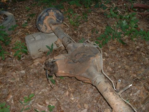 1985 Ford Bronco - A detached rear axle assembly rests on the forest floor, showing signs of wear and tear.