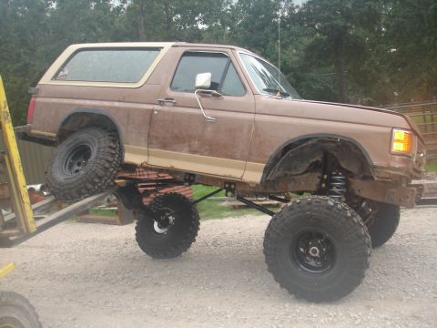 1987 Ford Bronco - This lifted 1987 Ford Bronco features oversized tires and a modified suspension system, giving it an aggressive off-road stance.