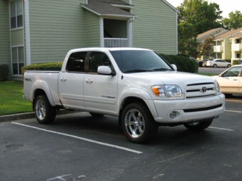 1986 Ford F-150 - A white Toyota Tundra pickup truck is parked in a lot with apartment buildings in the background.