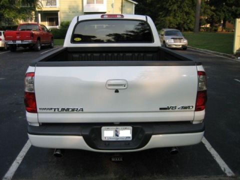 1986 Ford F-150 - Rear view of a white Toyota Tundra pickup truck parked in a lot, with another red truck and a silver sedan in the background.