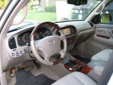 1986 Ford F-150 - The interior of a Toyota Tundra shows its dashboard, steering wheel, and center console with wood accents and a navigation system.