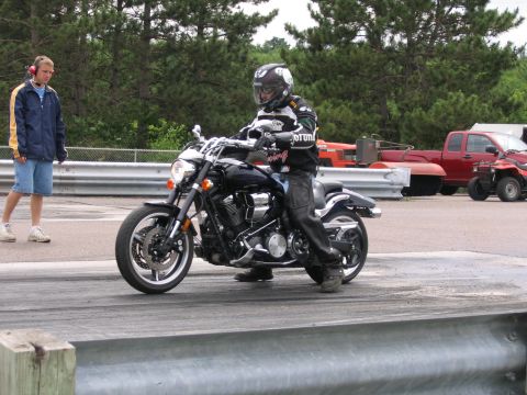 1989 Ford Mustang - A motorcycle rider prepares for a run on the drag strip with a spectator and other vehicles present.