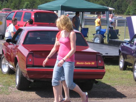 1989 Ford Mustang - Rear view of a red Monte Carlo SS at an outdoor event. Other cars and people are present.
