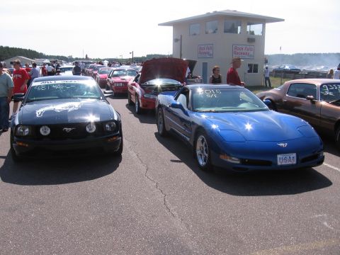 1989 Ford Mustang - A black Ford Mustang is parked in front of other vehicles at a race track.