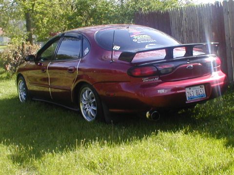 1998 Ford Taurus - Rear view of a 1998 Ford Taurus sedan parked on grass, a spoiler and custom license plate.