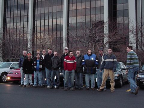 1998 Ford Taurus - A group of men pose for a photo in front of a modern office building, with several cars parked in the foreground.