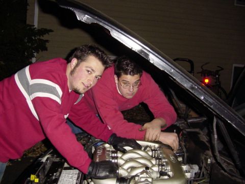 1998 Ford Taurus - Two men are seen working on the engine of a car with the hood open.