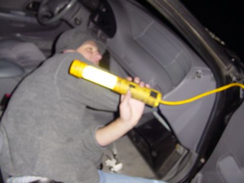 1998 Ford Taurus - Someone is working on the interior of a vehicle with a bright yellow work light.