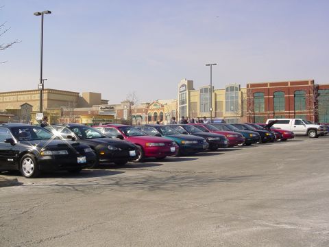1998 Ford Taurus - A row of sedans, some appearing to be from the late 1990s, are parked outside a shopping center.