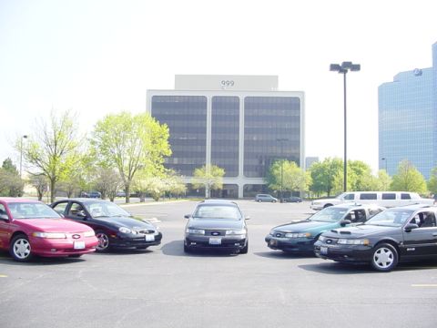 1998 Ford Taurus - A group of Ford Tauruses are parked in a lot outside of office buildings.