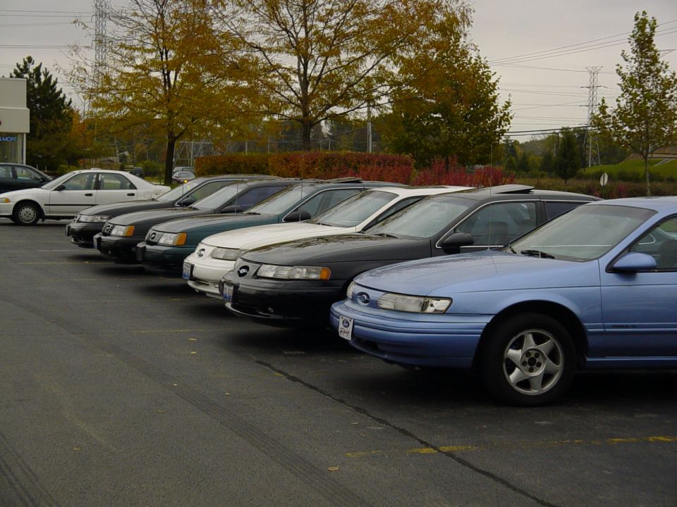 Line of 1998 Ford Taurus sedans parked in a lot, front view