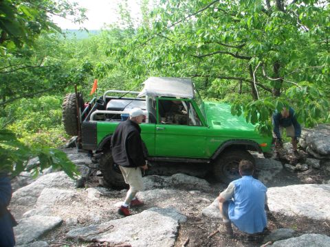 1992 Ford Bronco - A green Bronco navigates a rocky trail with several people observing the action.
