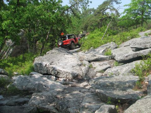 1992 Ford Bronco - A red 1992 Ford Bronco tackles a challenging rocky off-road course.