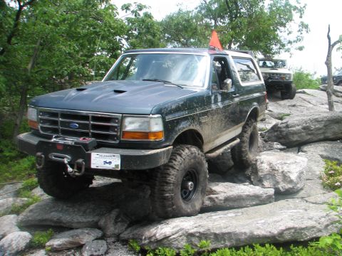1992 Ford Bronco - Ford Bronco tackling a challenging rock crawling course, with a second Bronco visible in the background.