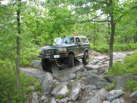 1992 Ford Bronco - This 1992 Ford Bronco tackles a challenging off-road course with large rocks and dense foliage.