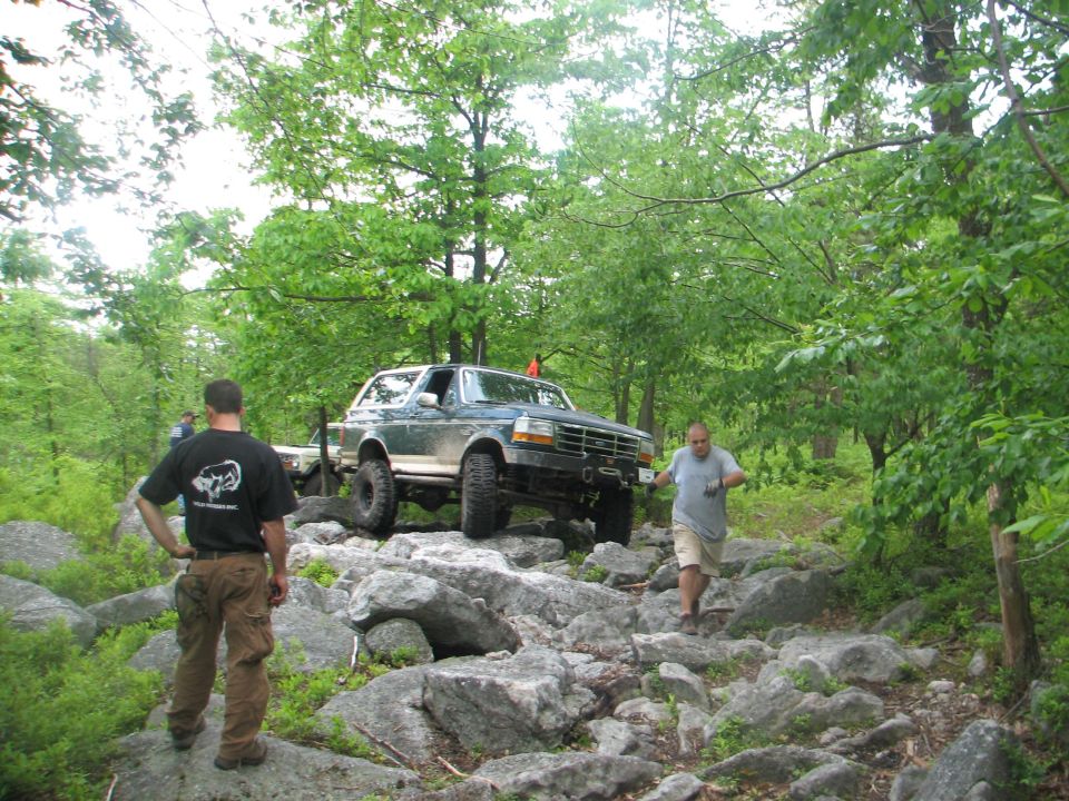 Green 1992 Ford Bronco navigating a rocky trail with two men nearby
