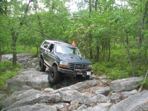 1992 Ford Bronco - Ford Bronco tackling a challenging off-road course through a dense forest.
